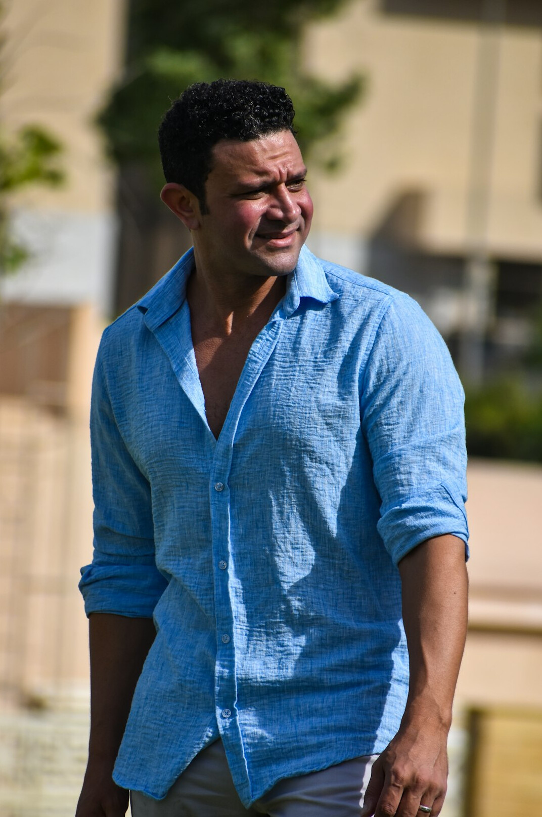 Smiling man with short dark hair and light stubble in a casual shirt