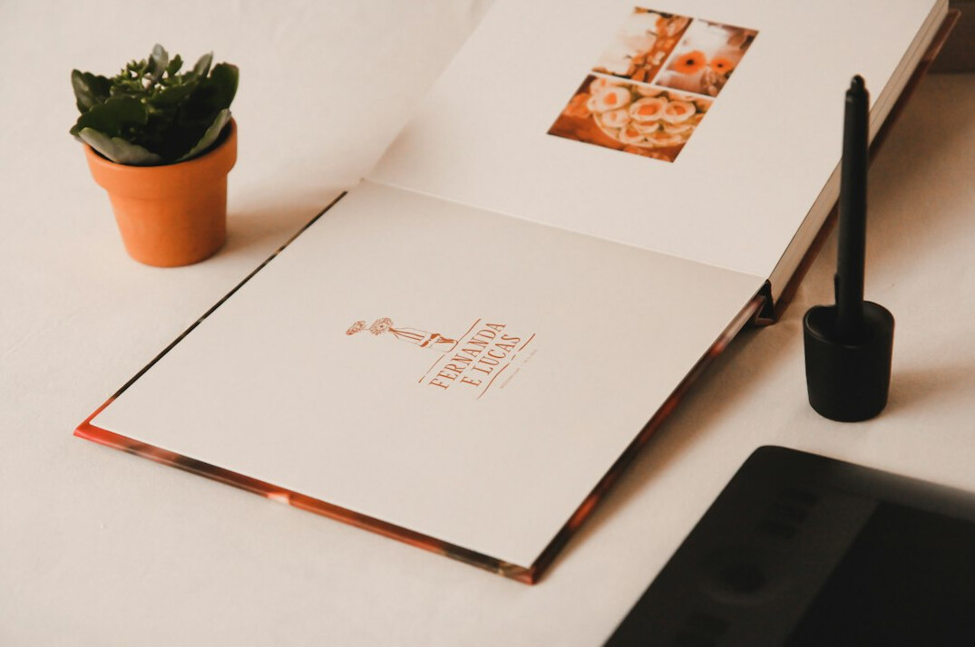 Laptop and open notebook on a bright wooden desk with a cup of coffee